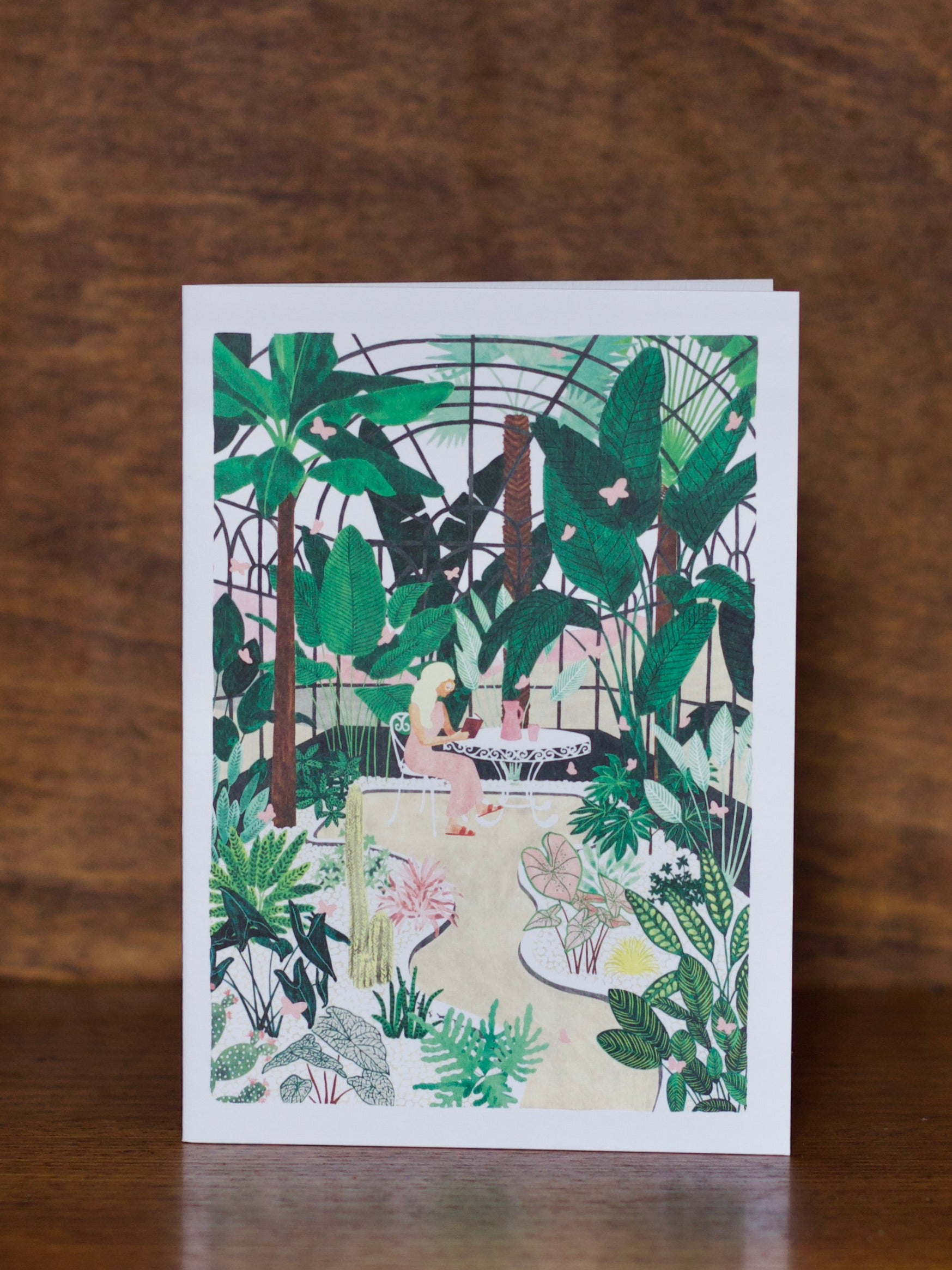 All Occasions greeting cards with a tropical design featuring a woman in a garden setting on a wooden surface.