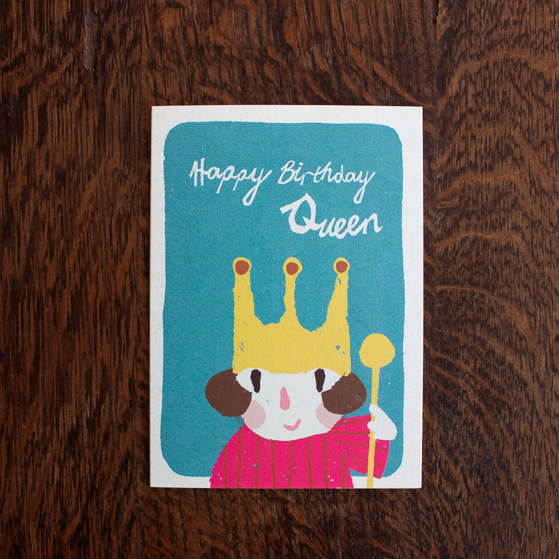 Florence Fry birthday greeting card with a cartoon character wearing a yellow crown and text 'Happy Birthday Queen' on a wooden surface.