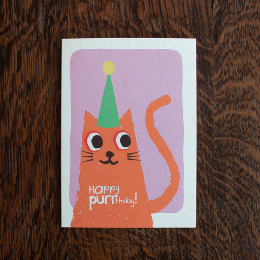 Florence Fry birthday greeting card with a cartoon cat wearing a party hat on a wooden surface