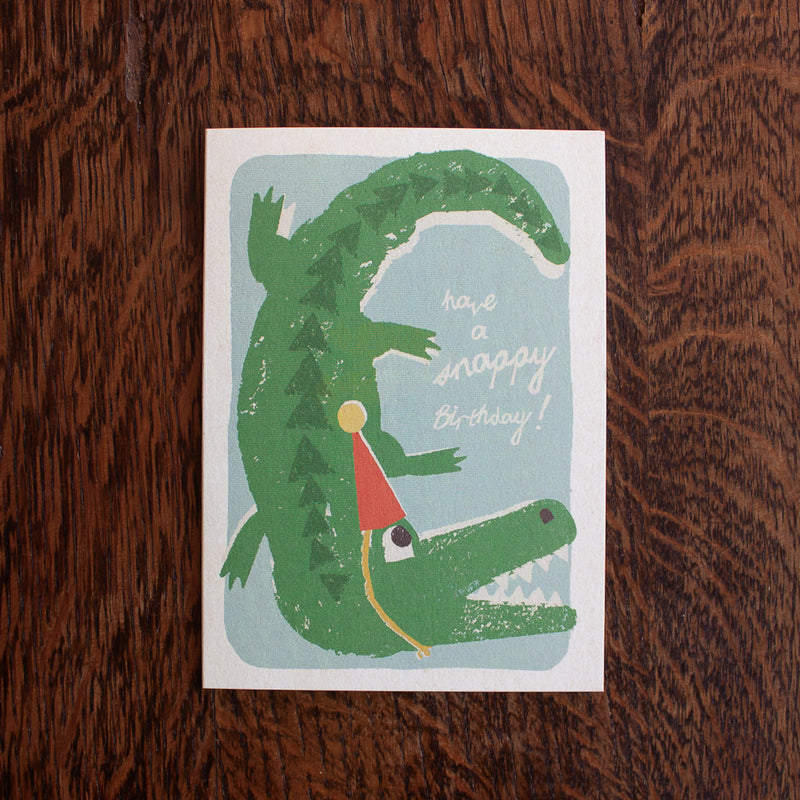 Florence Fry birthday greeting card with a crocodile illustration and text on a wooden surface