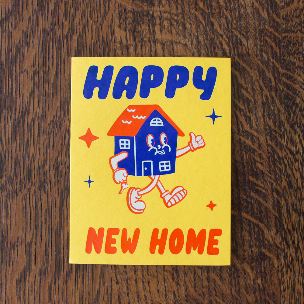Happy New Home card with a cartoon house on a wooden surface
