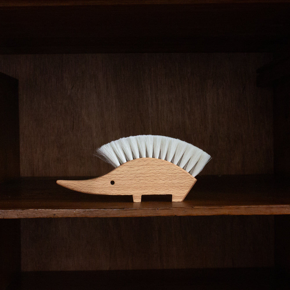 Wooden hedgehog-shaped brush with bristles on a wooden shelf