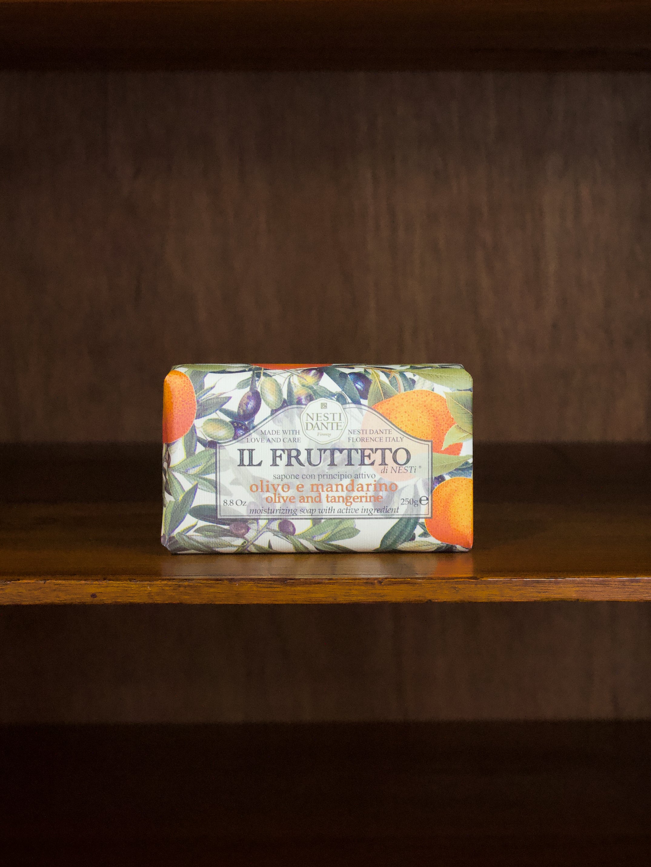 Il Frutteto olive and tangerine bar of soap with a colorful label on a wooden surface