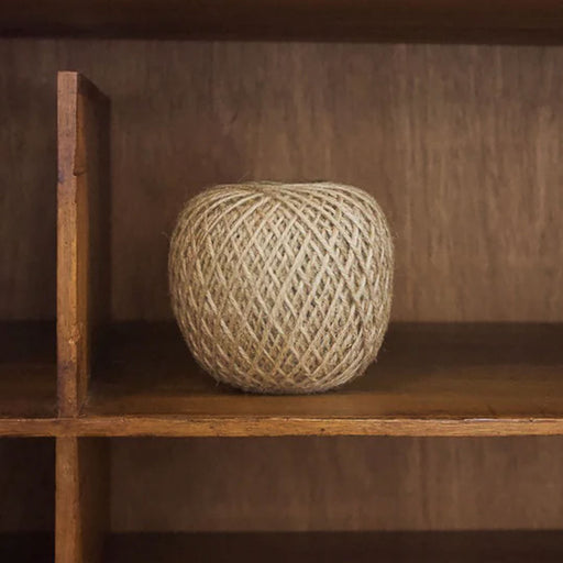 Ball of twine on a wooden shelf with a warm brown background