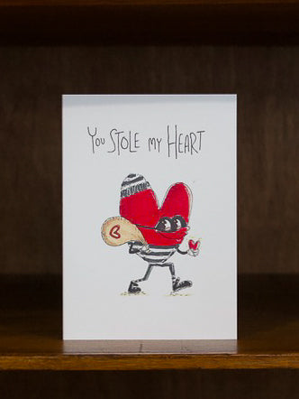 Well Drawn greeting card with illustration of a heart character and text 'You Stole My Heart' on a wooden surface.