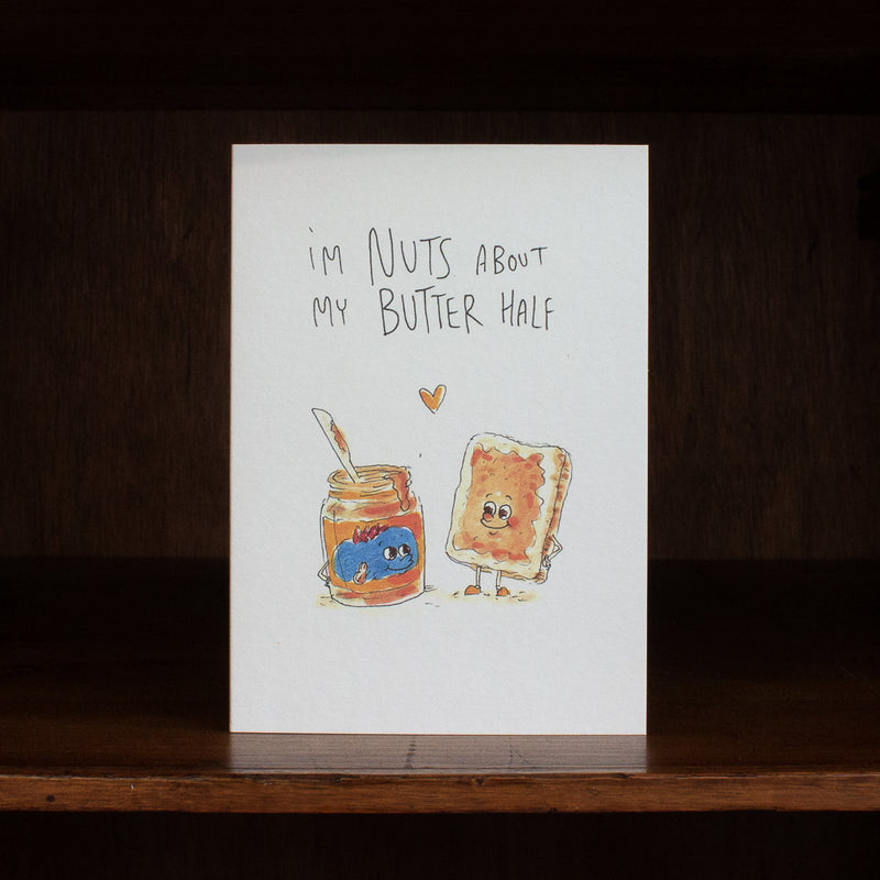 Well Drawn greeting card with cartoon characters of a jar of peanut butter and a piece of bread with jelly, text 'I'm nuts about my butter half', on a white background.
