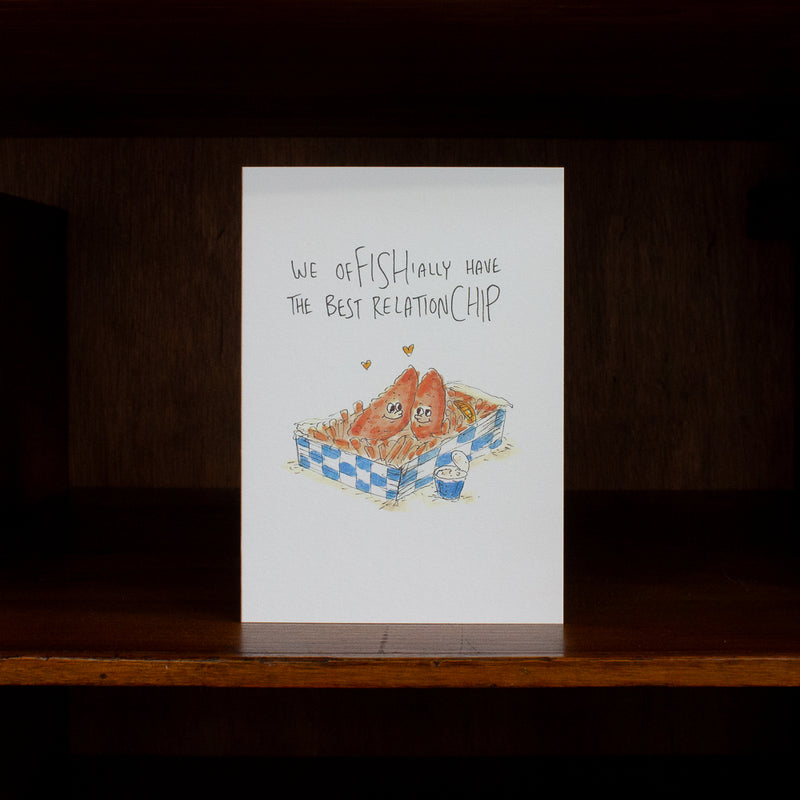 Anniversary & love greeting card with fish and chips illustration and text on a wooden surface