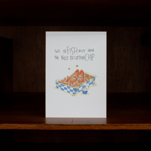 Anniversary & love greeting card with fish and chips illustration and text on a wooden surface