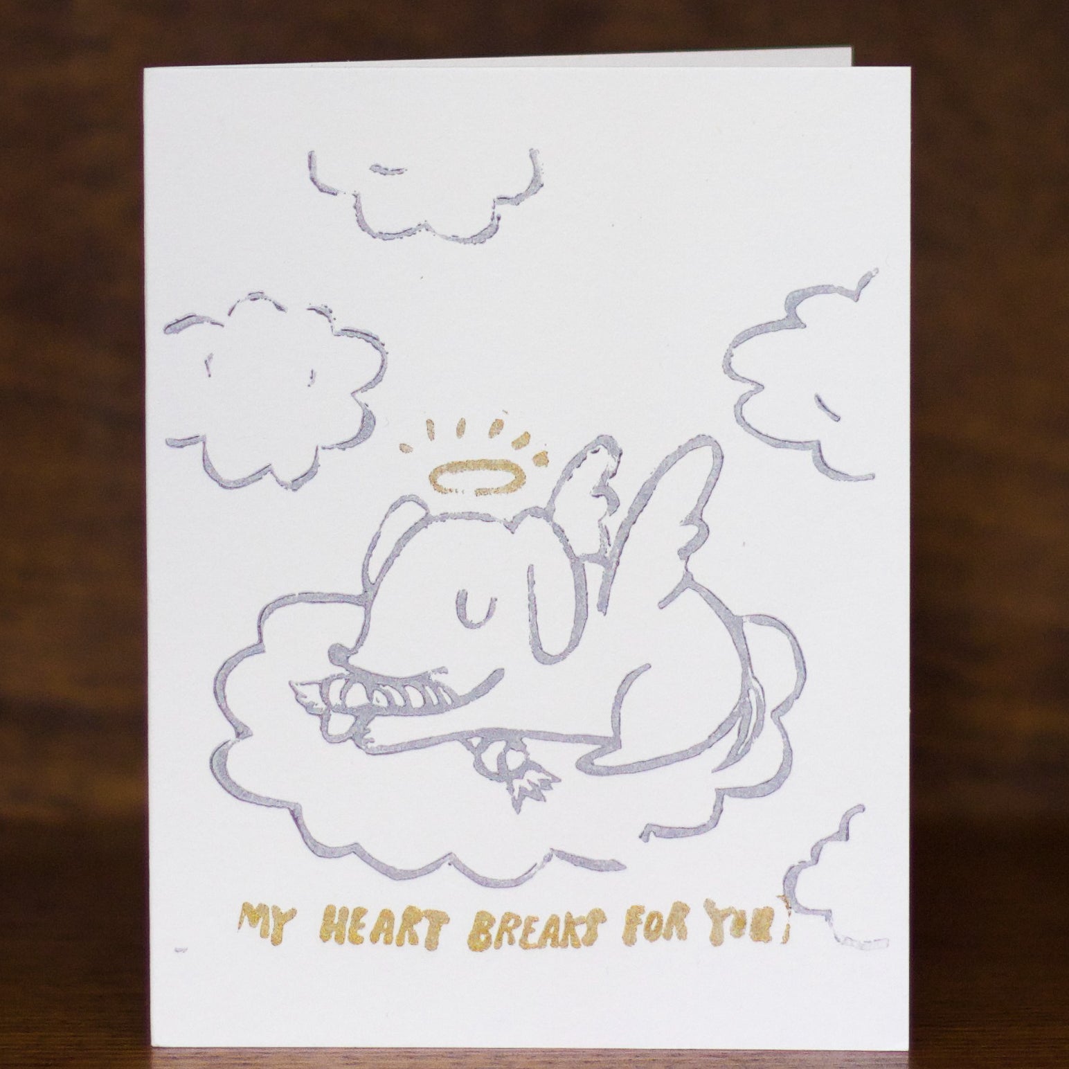 Pet Sympathy Greeting card by Ghost Academy with an illustration of a dog in clouds and text 'My heart breaks for you' on a wooden surface.