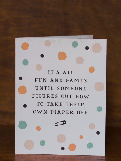 Baby greeting card with polka dot pattern and humorous text on a wooden surface