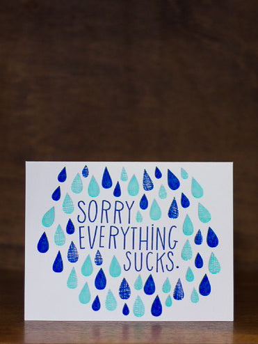 Sympathy greeting card with blue and green raindrop pattern and text 'Sorry Everything Sucks' on a dark background